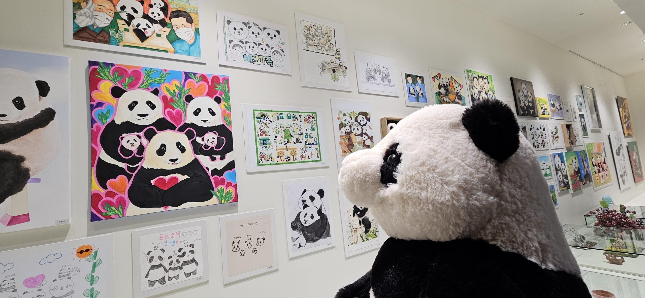 A Fu Bao plushy admires one of the pieces of fan art.