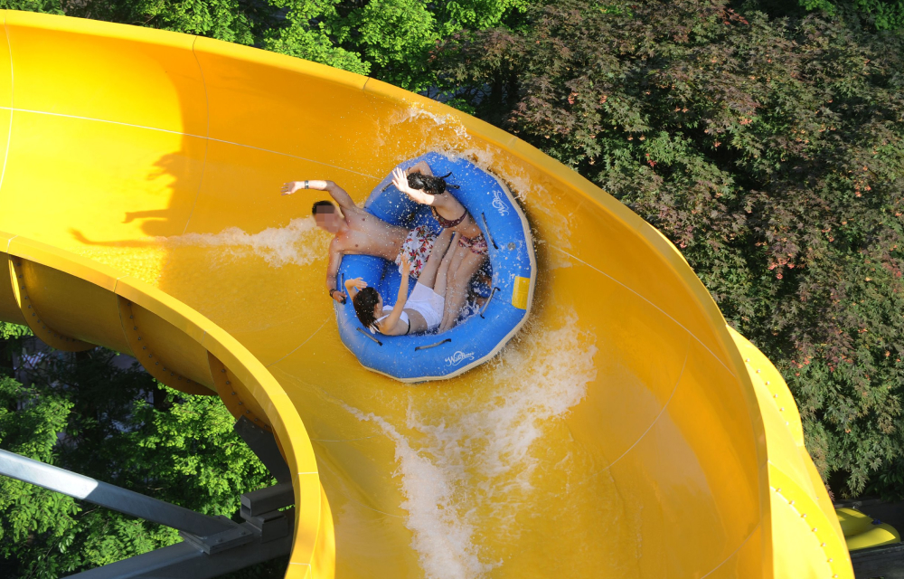 Group of 4 adults slide down a water park ride in a water raft at Everland’s Caribbean Bay in South Korea