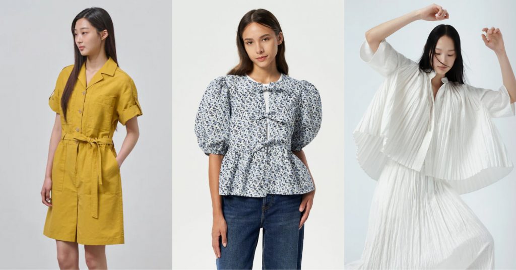 A woman wears a mustard color short sleeve jumpsuit and looks away from the camera, another woman wears a blue floral blouse and jeans and poses casually. A woman rasies her arms in a fashion pose wearing a flowy white skirt and blouse.
