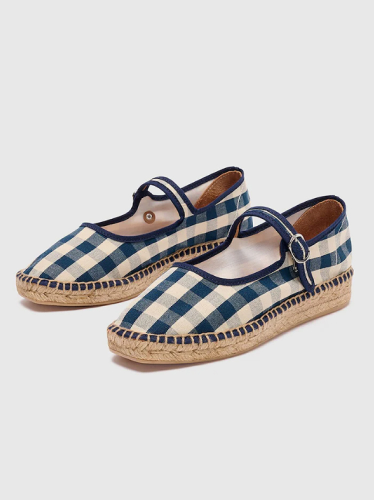 A pair of navy and cream gingham mary jane shoes with a buckle strap and an espadrille sole by the Spanish brand Naguisa.