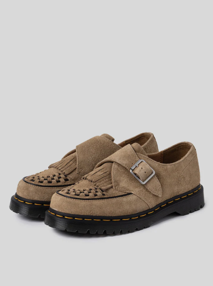 A pair of natural colored creeper loafers by the brand Dr. Martens with a braided detail on the tips of the shoes for added texture.