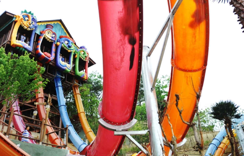 The colorful and translucent water slide capsules at Korea’s Caribbean Bay water park with one person sliding upwards with their body inverted.