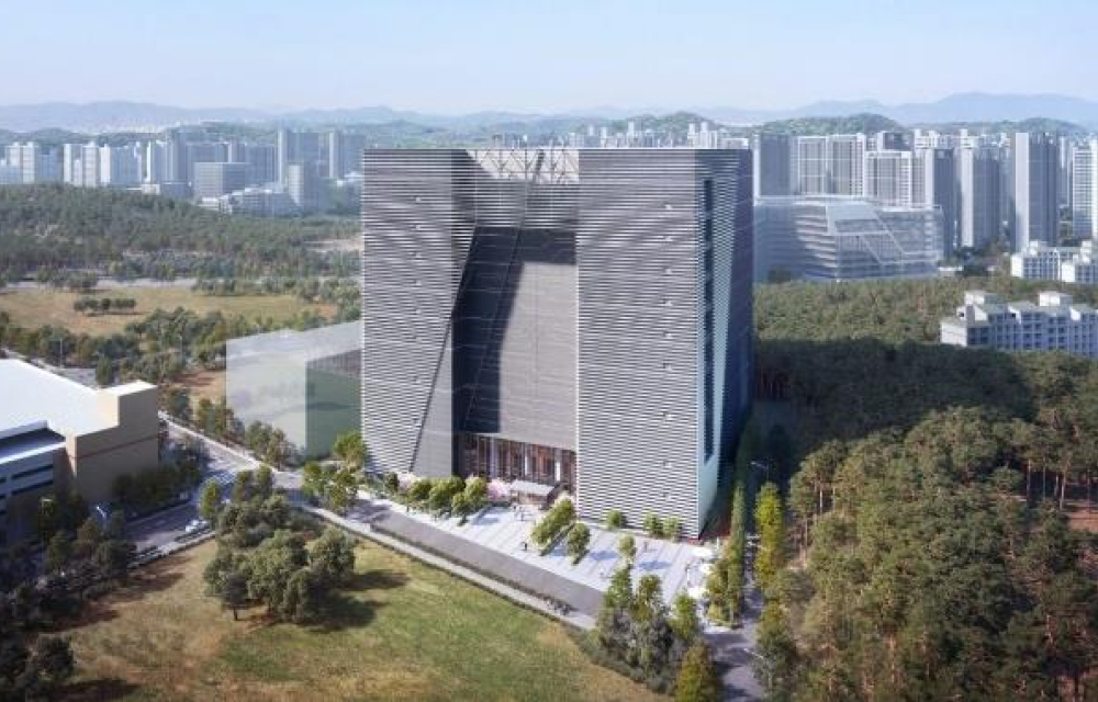 A unique data center building stands tall surrounded by trees and greenery in a city suburb, the building has a striped metal facade with a large cutout in its center that creates shadows and dimension.