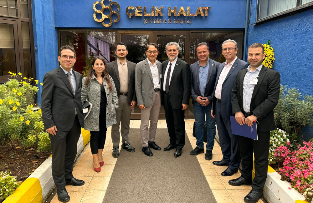 Employees stand outside a building to pose for a photo together after a business meeting wearing suits and formal attire.