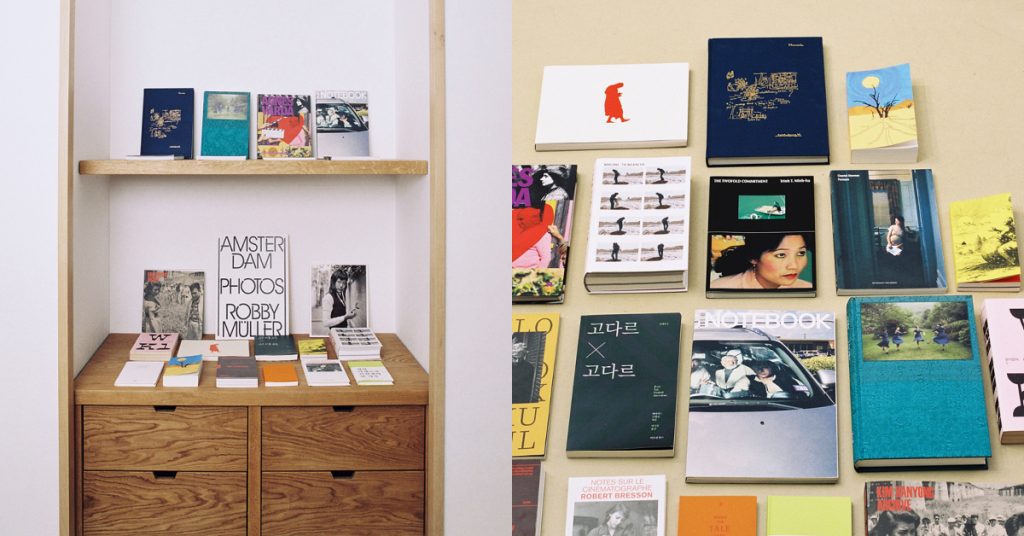 A selection of colorfully designed books in Korean and English are displayed on a wooden shelf and are spread out on a flat surface organized neatly.