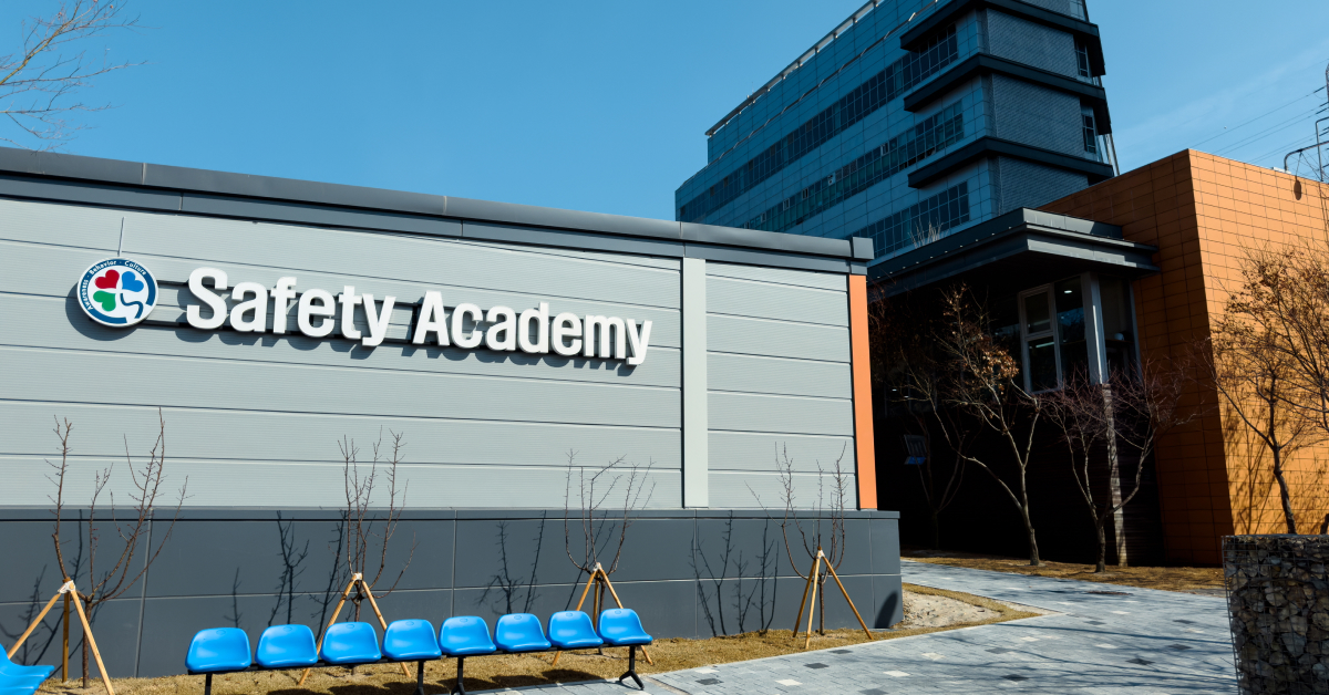 A building with a sign that says ‘Safety Academy’ on it, surrounded by small trees and a footpath.