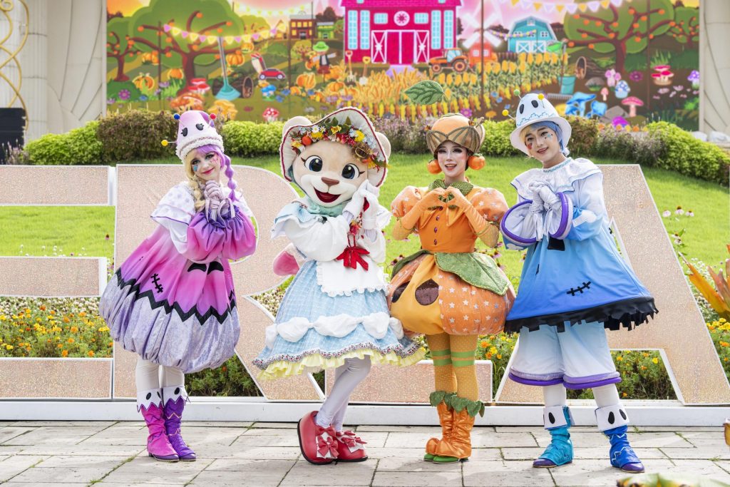 Four actors dressed in brightly colored costumes pose together for a photo. The characters are wearing cute outfits with large shapes and bold colors and are ready for a performance!