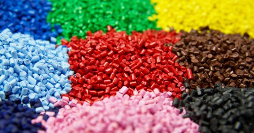 Nine piles of colorful plastic pellets sit neatly next to one another in a grid like formation; the colors include blue, green, yellow, pastel blue, red, brown, navy, pink, and black.