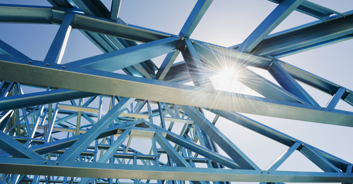 Close-up view of a blue steel framework structure with sunlight shining through, representing the strength and durability of steel in construction and industrial applications.