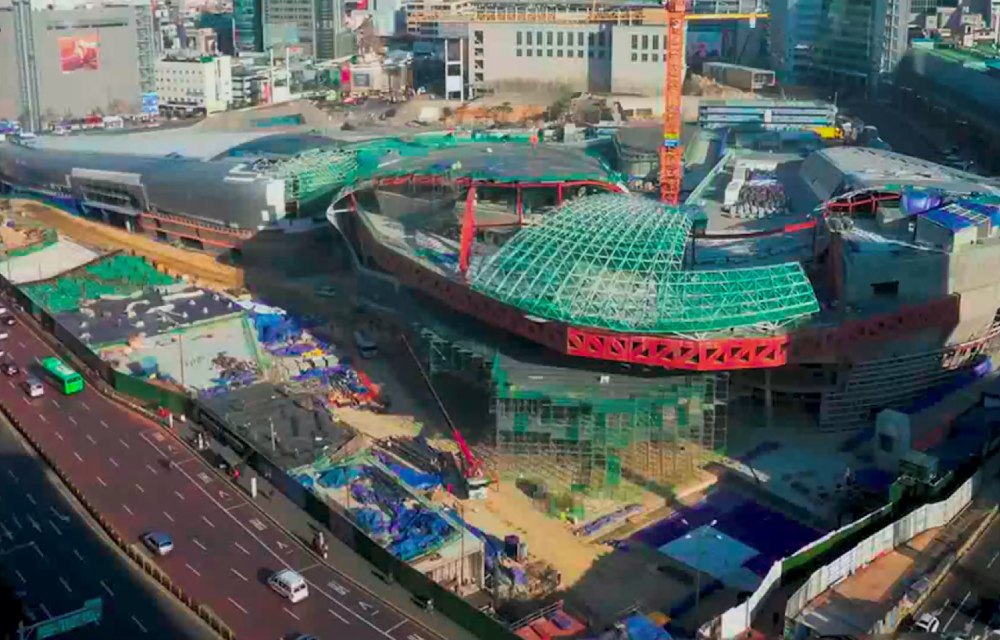 A wide shot of the DDP’s construction is well underway with metal exterior panels curving around 50% of the structure with lattice structures taking shape of the final curved form which will become the world’s largest 3D amorphous structure.