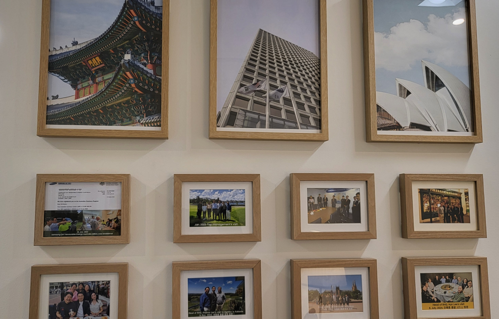 Eleven framed photos hang on a wall at the Samsung C&T Sydney branch office; the images consist of Korean and Australian landmarks and images with partners during milestone projects.