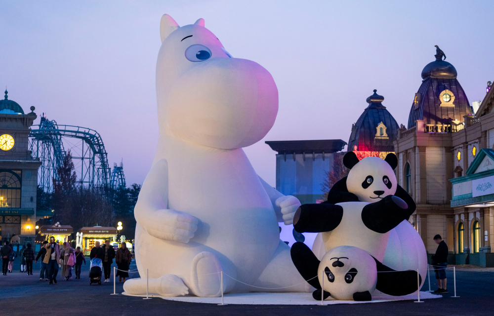 Giant Moomin and panda statues at dusk – Large illuminated Moomin and panda figures create a cozy evening vibe.