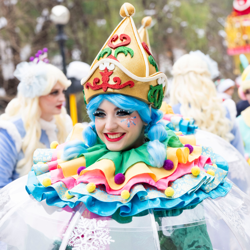 Performer in colorful fantasy costume – Close-up of a smiling performer in a whimsical, bright costume.