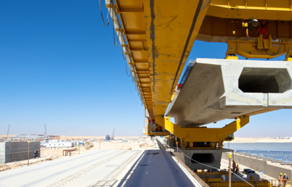 A cross-sectional view of a Full Span Launching Method (FSLM) construction process, where a massive yellow gantry crane lifts and positions a pre-cast concrete segment for an elevated bridge or metro track.