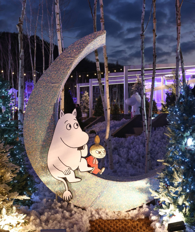 A moon-shaped display featuring Moomin and Little My in Everland's Nordic Forest, surrounded by birch trees and illuminated winter decorations at dusk.