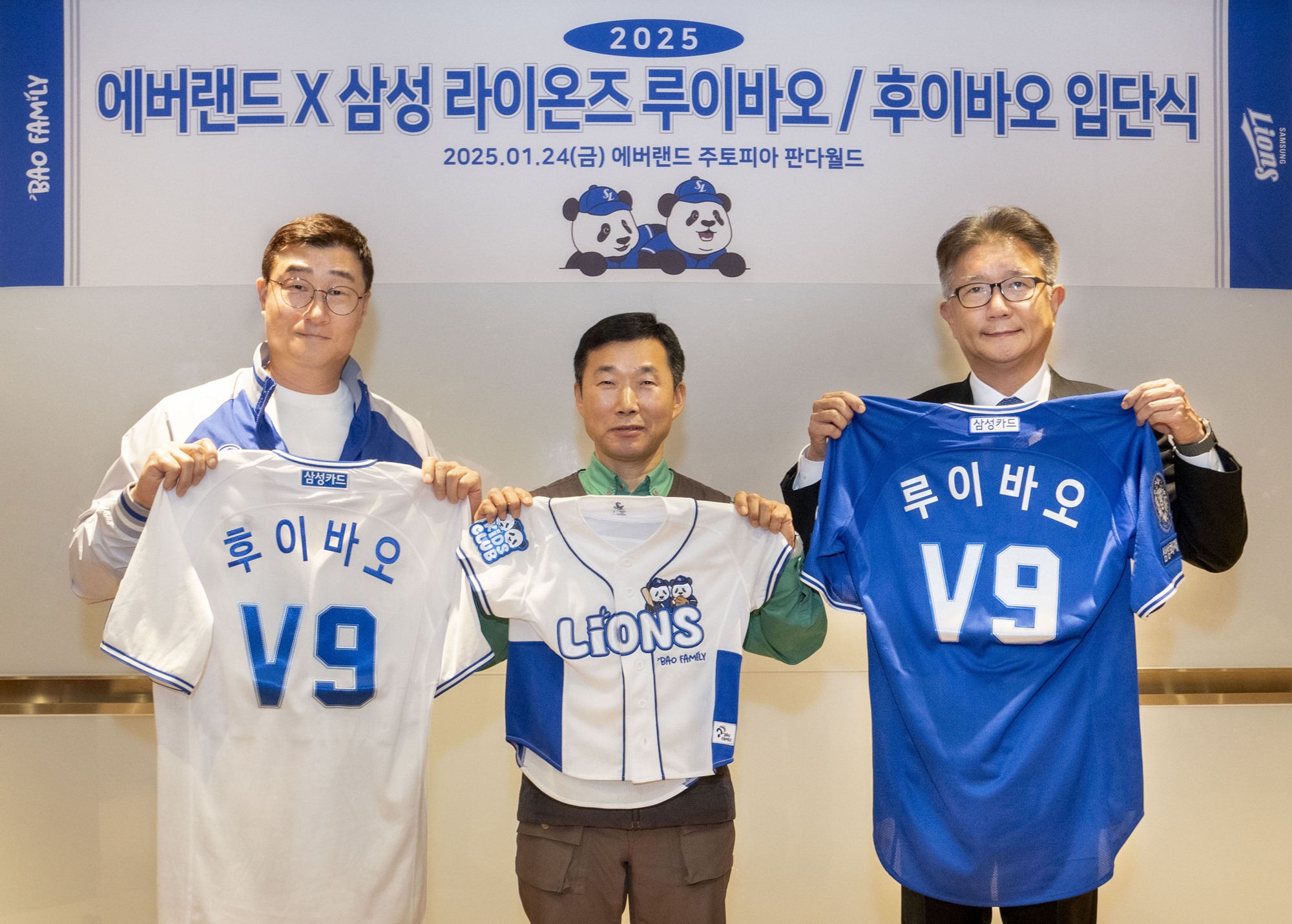 Three men stand in front of a backdrop featuring Everland and Samsung Lions branding, holding up custom jerseys with the names "Rui Bao" and "Hui Bao" printed on them. The jerseys symbolize the honorary induction of the panda characters into the Samsung Lions team.