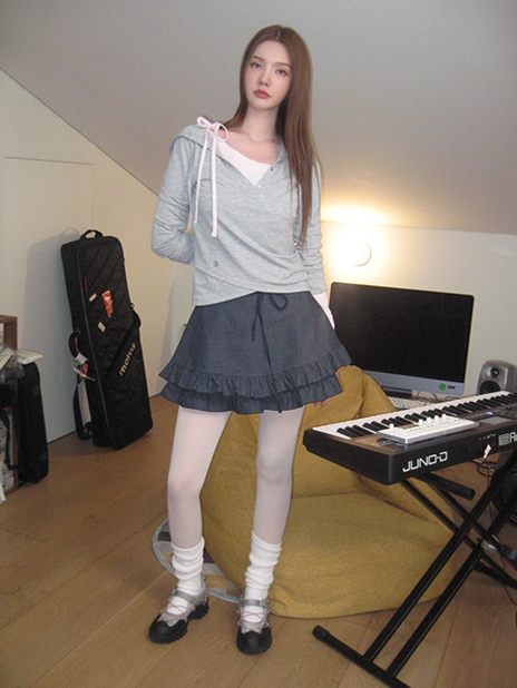 xooos showcases the fourth look of the third drop from the 8seconds x xooos collaboration, wearing a Wrap Hooded T-Shirt in Grey with a ruffle-layered skirt. The outfit is styled with white tights, leg warmers, and delicate ballet-inspired flats, creating a cozy yet effortlessly chic ensemble with nostalgic, soft-girl aesthetics.