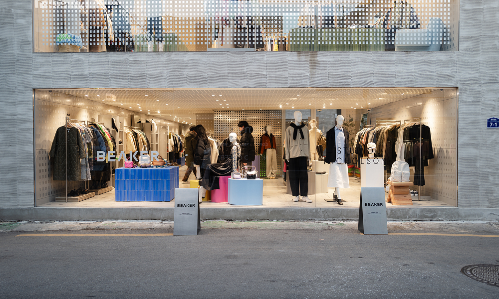 BEAKER's flagship store in Seongsu with a textured concrete facade and large glass windows displaying contemporary fashion pieces, seamlessly blending into the industrial surroundings.