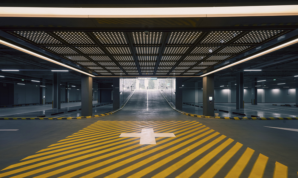 A well-lit residential parking space at High-End ONE PARK with bold yellow-striped crosswalks. The structured ceiling and reflective floor enhance visibility, ensuring safety and ease of navigation for residents.