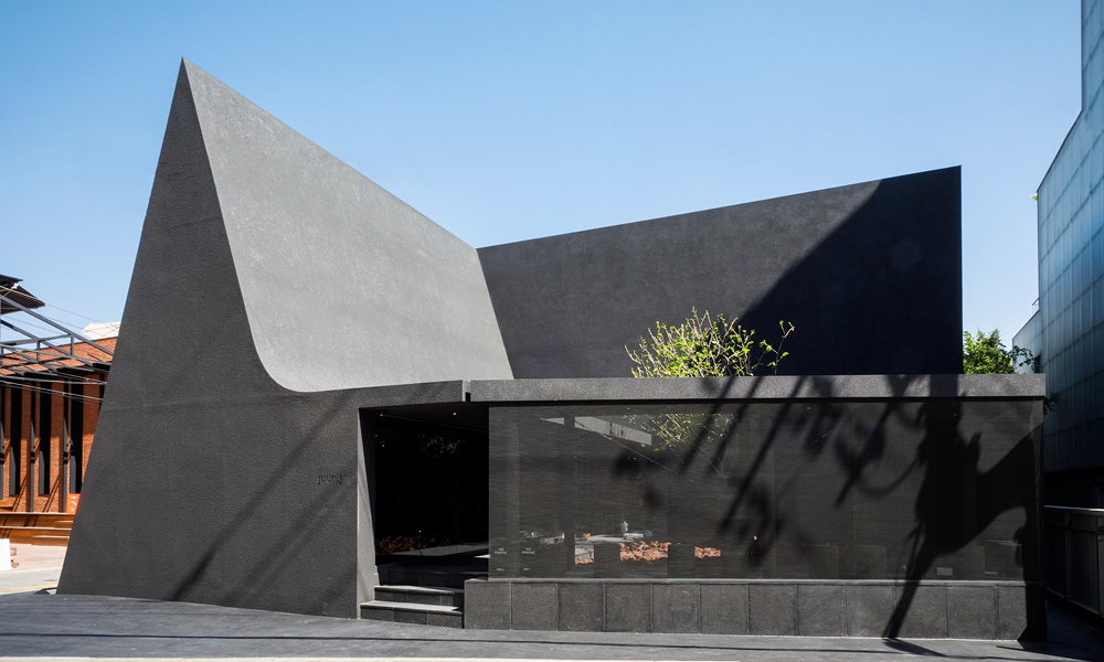 Exterior view of Juun.J's Dosan Park flagship store in Seoul, showcasing a modern black angular structure inspired by traditional Korean Hanoks.