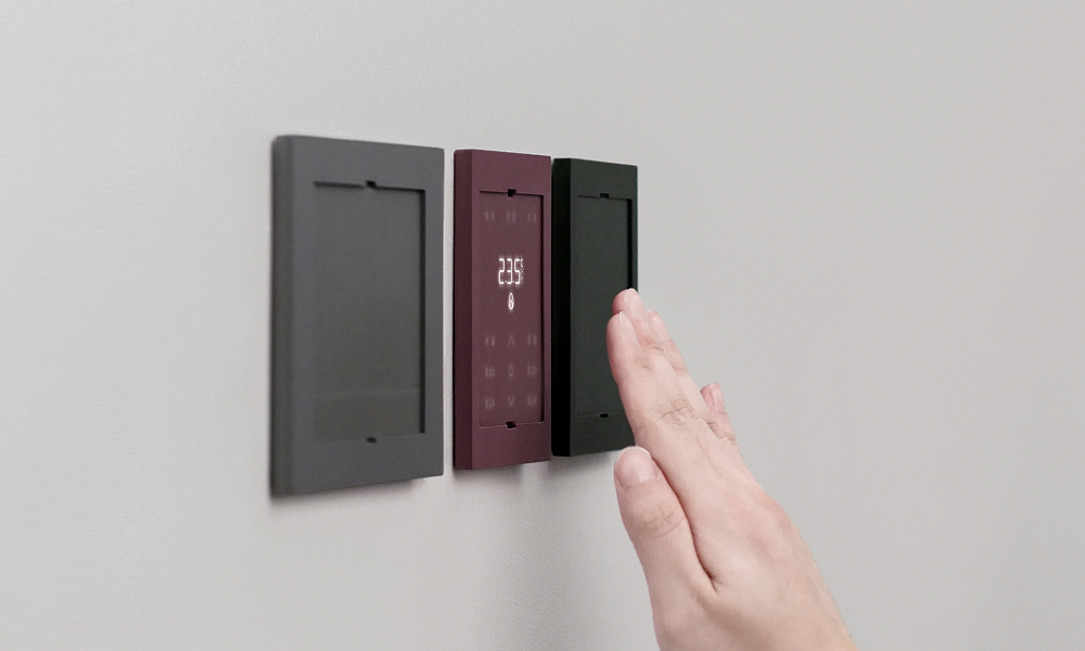 A close-up of a person’s hand interacting with Samsung C&T’s LESS ENERGY SWITCH SYSTEM. The sleek, minimalist energy-saving switches are mounted on a wall, featuring a dark gray and burgundy panel with an intuitive touch interface designed to control apartment lighting and power outlets efficiently.