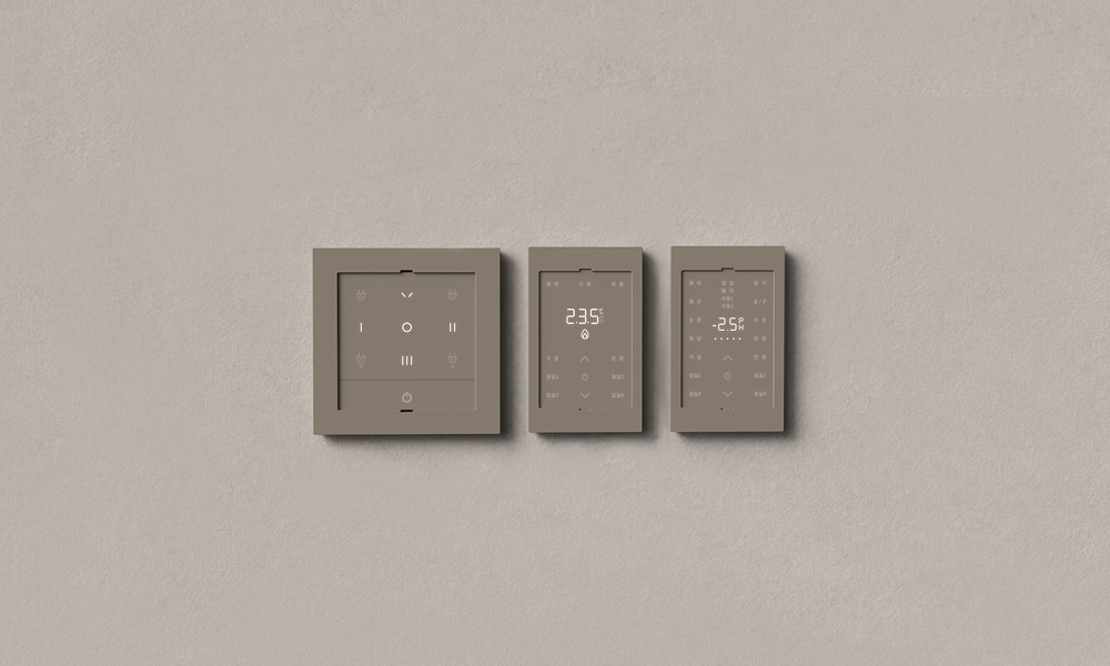 A set of three Samsung C&T LESS ENERGY SWITCH SYSTEM panels displayed on a neutral-colored surface. The switches feature a modern, minimalist design with a user-friendly interface, recognized for their energy-saving capabilities and sustainable materials.