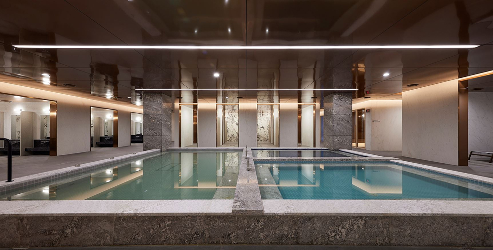 A luxurious indoor sauna and pool area at Raemian One Bailey The Brillia, inspired by Finnish sauna culture. The space features a sleek, modern design with a long rectangular pool, warm ambient lighting, and stone and wood accents that create a relaxing retreat for residents.