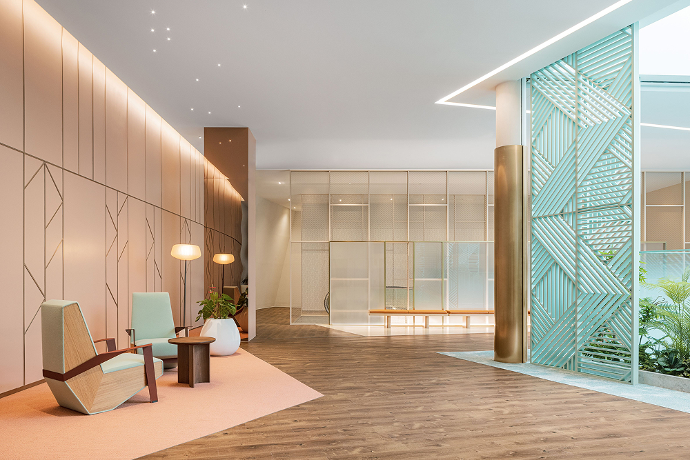 A futuristic apartment lobby designed as part of Raemian Universe by Samsung C&T. The space features a modern aesthetic with soft neutral tones, minimalist furniture, floor-to-ceiling glass panels, and geometric green lattice structures that add a dynamic and open feel.