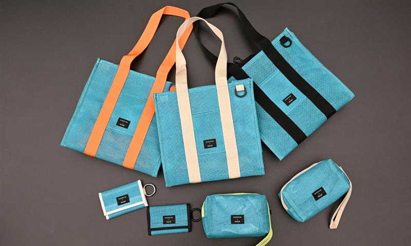 A collection of upcycled accessories from Samsung C&T E&C Group’s Raemian upcycled collection, including tote bags, pouches, and wallets. The items are turquoise with orange and black accents, made from repurposed vertical safety netting used on Raemian apartment construction sites.