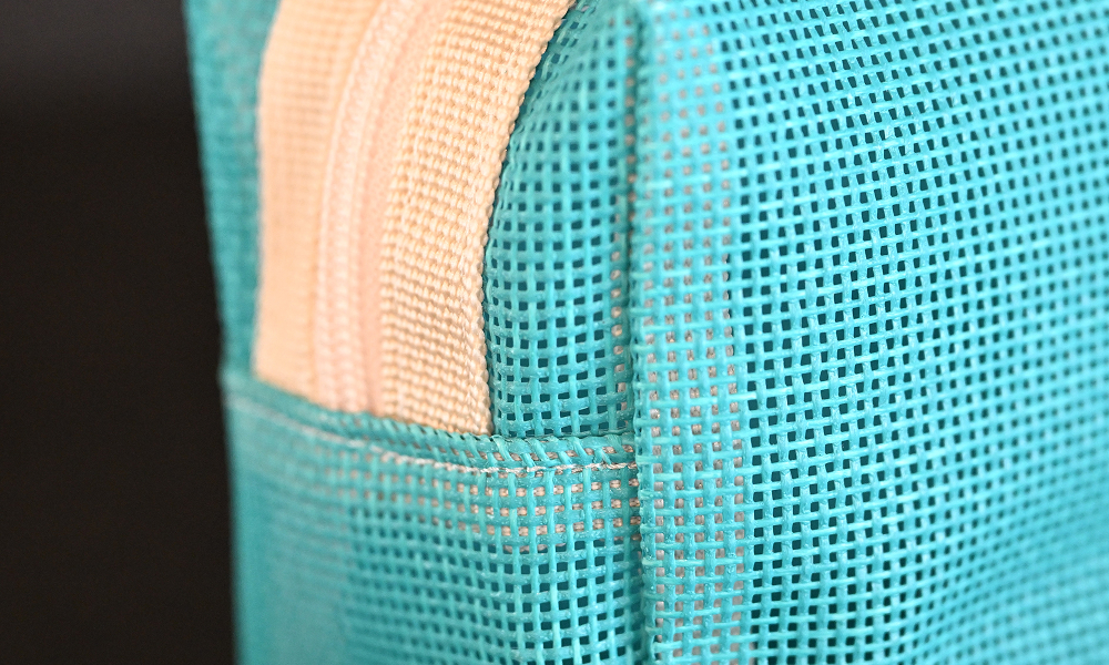 A close-up of the upcycled materials used in Samsung C&T E&C Group’s Raemian accessory collection. The detailed shot highlights the turquoise safety netting fabric, originally used on construction sites, repurposed into a stylish and sustainable product.