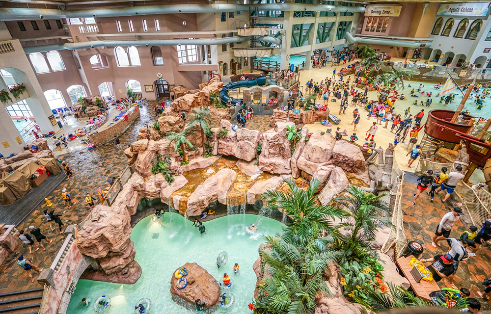 Families enjoy various attractions inside Caribbean Bay’s spacious indoor Aquatic Center, featuring pools, waterfalls, and tropical-themed decor.