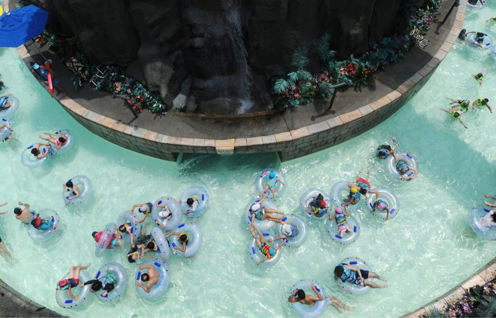 Dozens of guests relax in inner tubes as they float along the winding Lazy River at Caribbean Bay on a sunny day.