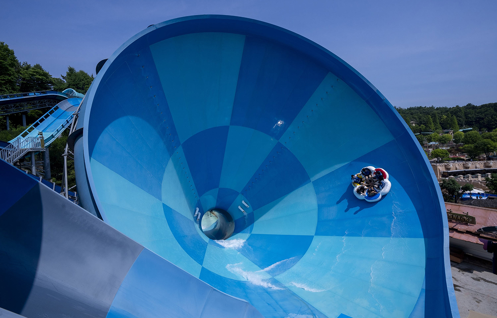 A group of riders in a circular raft descends the towering blue funnel of the Mega Storm water slide at Caribbean Bay.