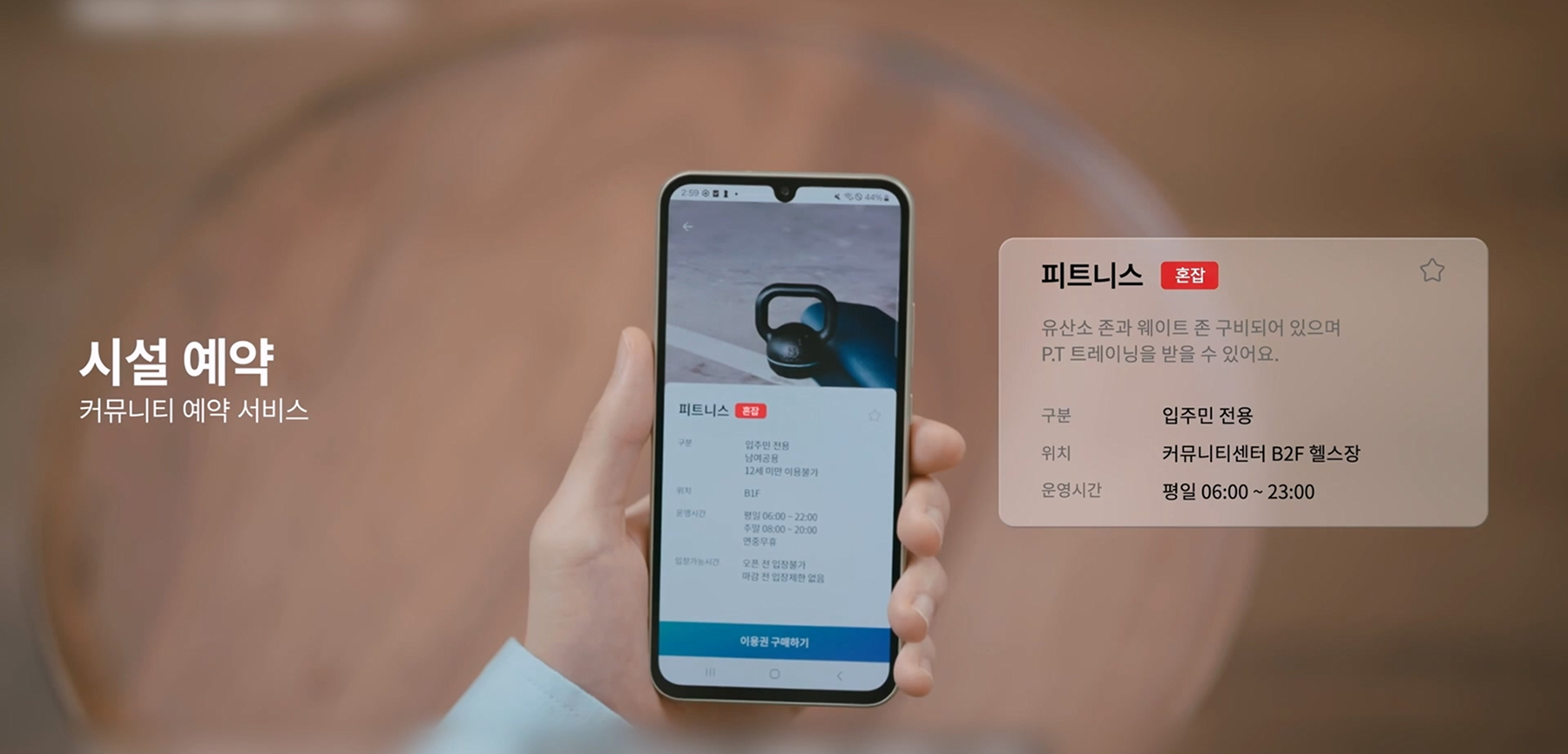 A close-up of a person holding a smartphone displaying the Homeniq app interface, Samsung C&T E&C Group’s smart home platform for managing various residential services.