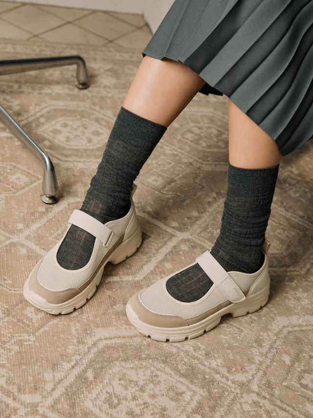 BEANPOLE ACCESSORY beige mary jane sneakers styled with dark grey socks and a grey pleated skirt.