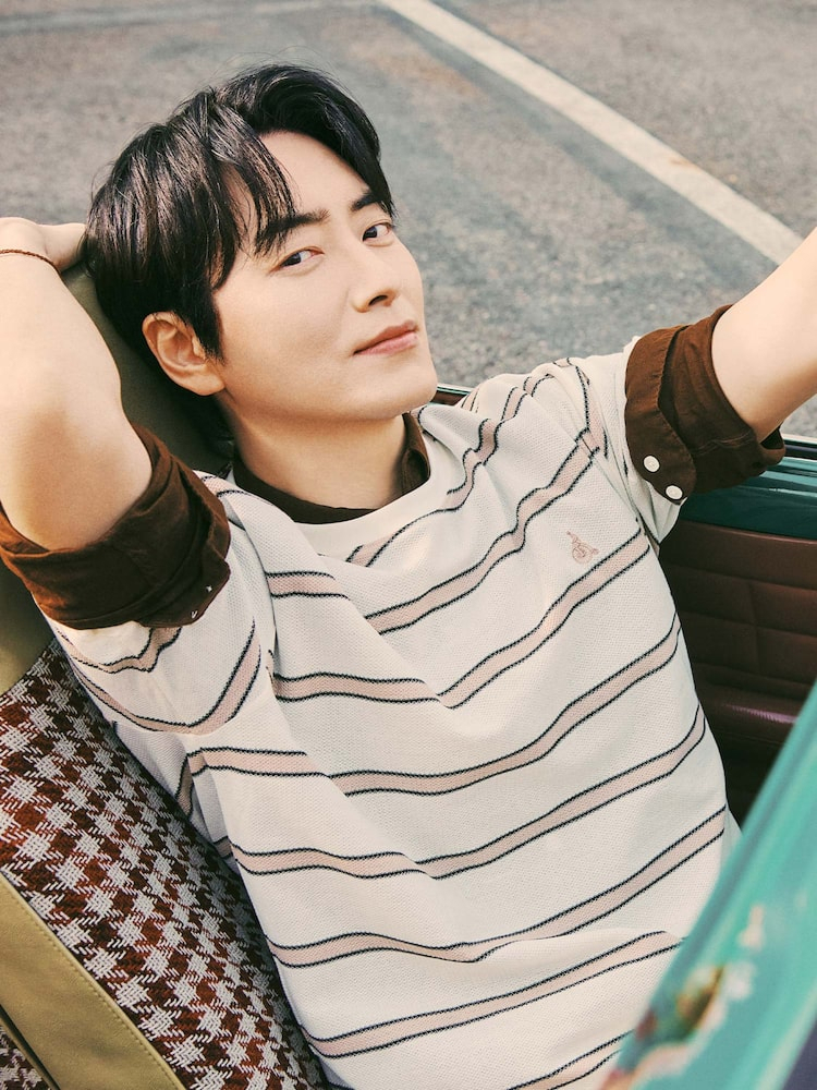 Male model lounges in the backseat of a vintage car wearing the Beanpole Men Linen Solid Shirt in brown, layered under a striped knit tee.
