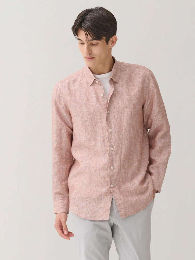 Male model wears the Galaxy Lifestyle linen pinstripe shirt in orange over a white T-shirt, paired with light grey trousers in a minimal studio setting.