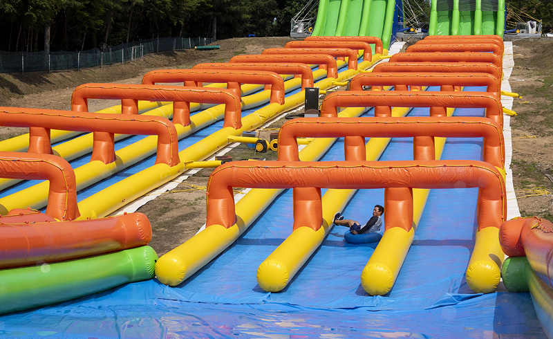 Wide view of a colorful inflatable water slide course at Everland Korea with a single rider sliding down in a blue tube.