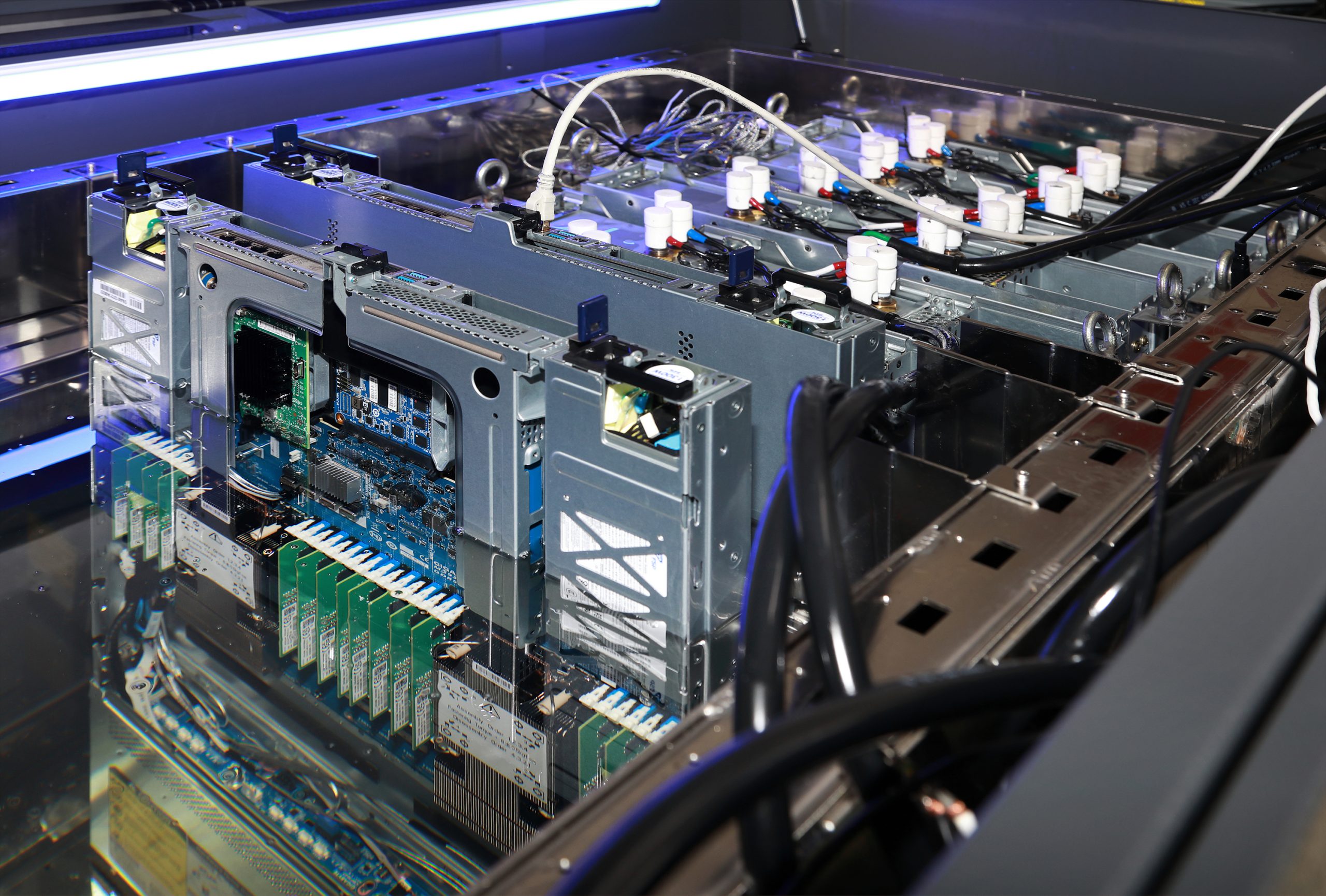 Servers submerged in transparent coolant within a tank, with visible components and connected cables.