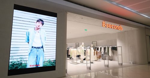 Exterior view of the 8 Seconds flagship store at SM Mall of Asia in the Philippines. The storefront showcases mannequins styled in light-toned outfits and a large digital screen displaying ENHYPEN’s Sunoo in a denim look for the campaign.