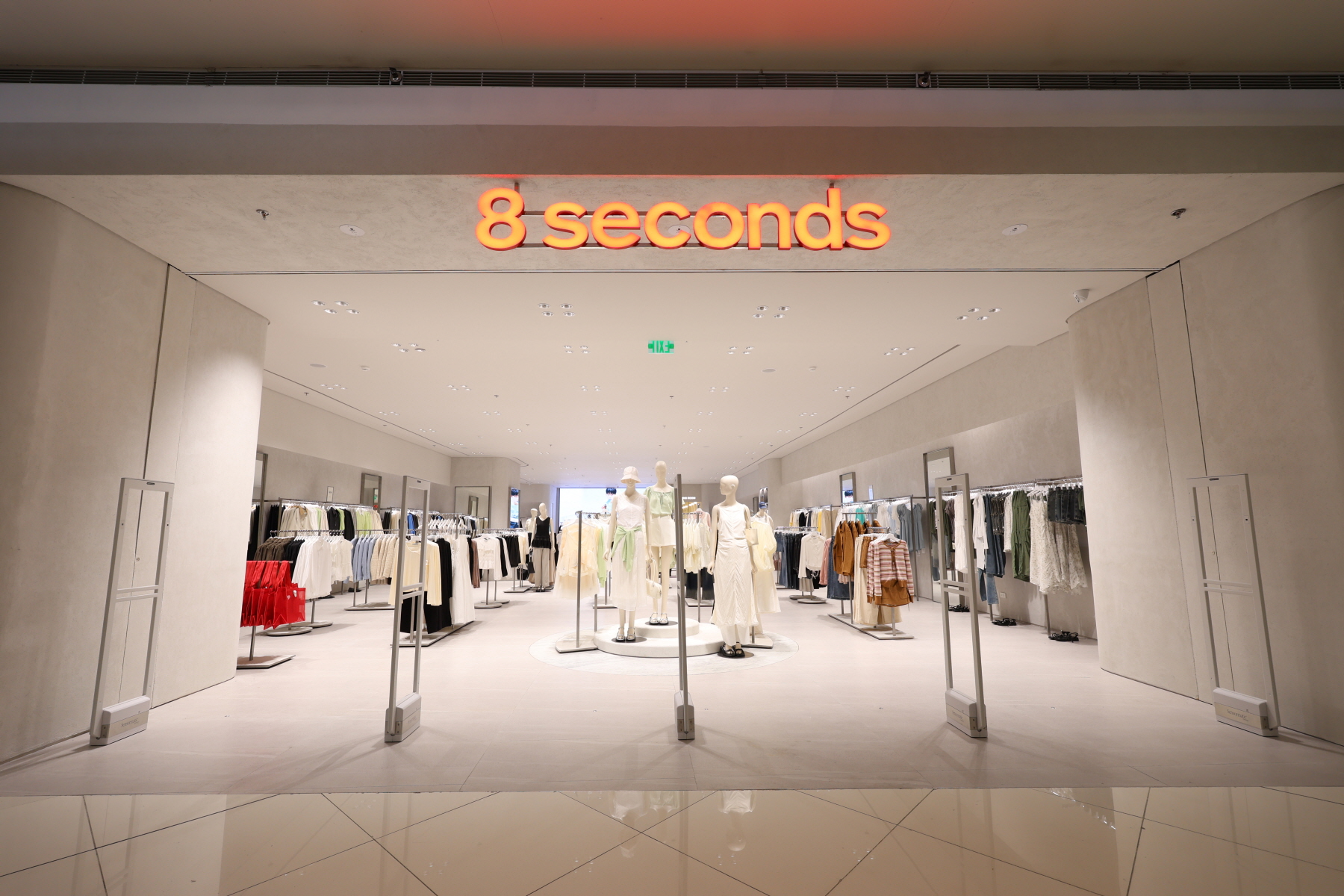 Interior view of the 8 Seconds store at SM Mall of Asia, showcasing neatly arranged clothing racks, mannequins in neutral-toned outfits, and a spacious, modern retail layout.