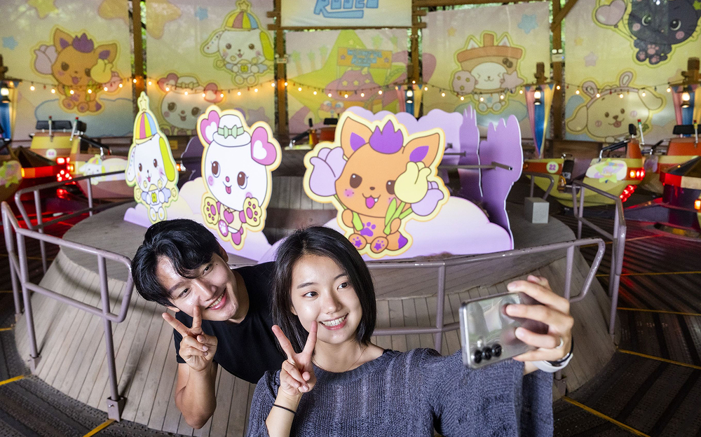Everland visitors take a selfie in front of pastel character cutouts and decorations inside the NCT WISH-themed Wishful Rodeo zone at Everland.