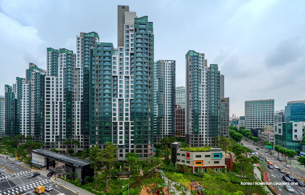 High-rise apartment buildings of Raemian Leaders One in Korea, surrounded by greenery and city roads.