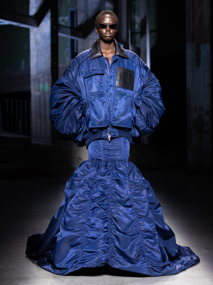 Model walks the runway in blue Juun.J workwear jacket and matching mermaid skirt with gathered detailing at Paris Fashion Week