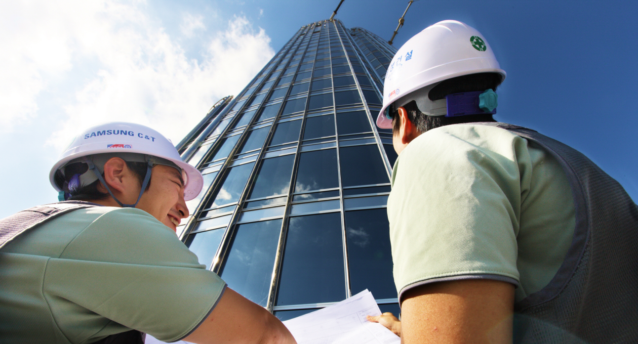 Samsung C&T Engineering and construction workers stand in front of a tall building at a construction site