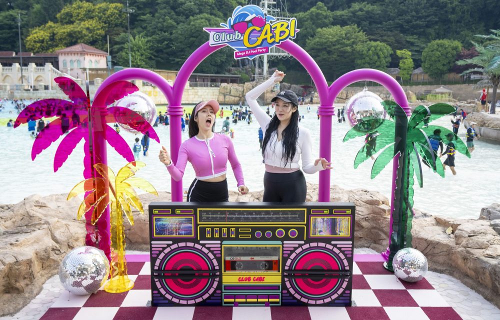 Water park guests enjoy a DJ booth photo zone as they pose in front of the park’s outdoor wave pool.