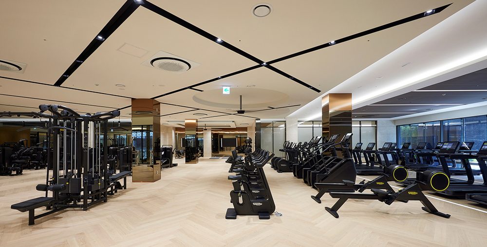A spacious and well-lit gym at Raemian One Bailey The Brillia, equipped with state-of-the-art fitness machines and free weights. The interior design incorporates neutral tones, high ceilings, and modern lighting, providing residents with a premium exercise environment.