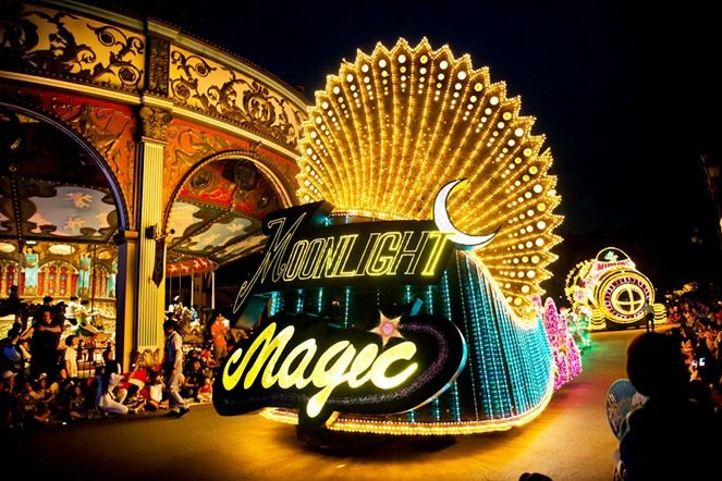 Brightly illuminated floats with glowing text and intricate light designs parade through Everland at night during the Moonlight Parade.