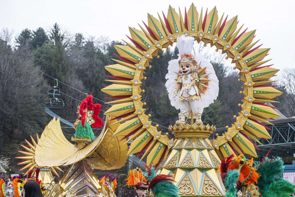 Everland’s mascot Lenny stands atop a golden float surrounded by sunburst decorations and dancers in colorful costumes during the Carnival Fantasy Parade.