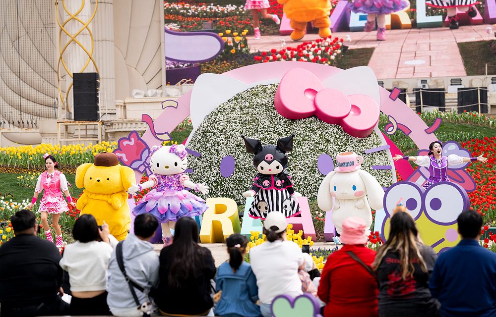 Families sit in front of a large floral Hello Kitty stage at Everland, watching Sanrio characters like Kuromi, Cinnamoroll, Hello Kitty, and Pompompurin perform during the Sanrio Characters Dance Time show.